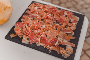 Prosciutto or jamon serrano. Close up on cutting traditional Italian Spanish ham. Slicing prepared hamon gastronomy background