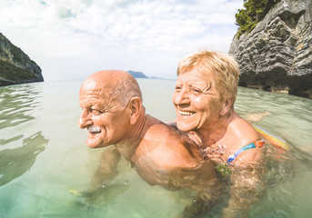 Senior couple vacationer having genuine playful fun on tropical beach in Thailand - Snorkel tour in...