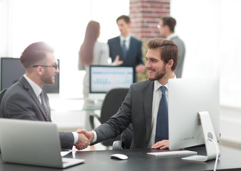 Successful managers shaking hands after closing deal in office