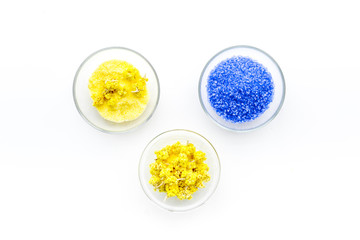 Colorful spa salt. Yellow spa salt with delicate spring flowers and violet lavender spa salt on white background top view copy space