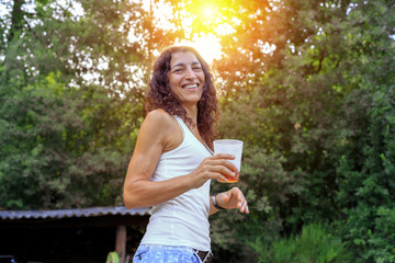 Naklejka premium Beautiful young woman holding soda and smiling at summer. Summer joy concept.