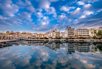 Fototapeta premium Agios Nikolaos Crete -Amazing view with reflections at Voulismeni lake. Dramatic sky with colorful buildings of one of the most popular touristic destination of Crete.