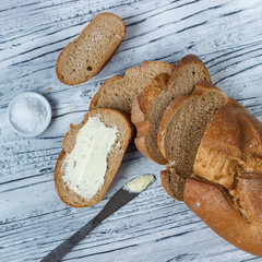 A slice of rye bread with butter on a wooden background is a close-up.