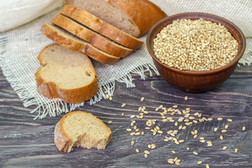 Fototapeta premium Slices of whole-wheat bread with wheat seeds on a wooden background