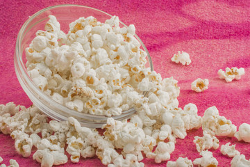 popcorn in a glass plate, on a pink background