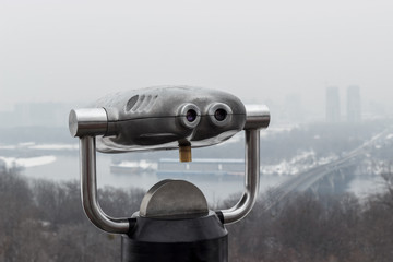 Binocular binoculars with binoculars, standing on the mountain, view of the city. A landscape with a beautiful cloudy sky, a bridge and a haze in the distance ..