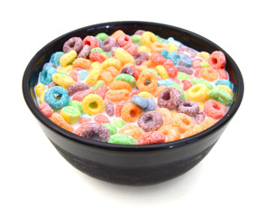Delicious and nutritious fruit cereal loops flavorful in black bowl and milk on white background, healthy and funny addition to kids breakfast