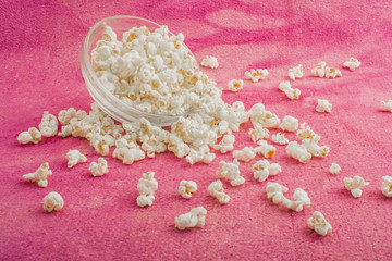 popcorn in a glass plate, on a pink background