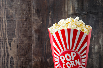 Popcorn inside the packaging striped on wooden table background. Copyspace
