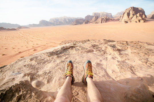 Jordan national park Wadi Rum desert. Beautiful view and panoramatic picture of man legs and outdoor shoes. Natural background. Sunset in a desert. 