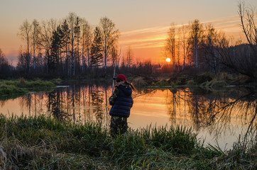 Obraz premium Woman fishing at sunset