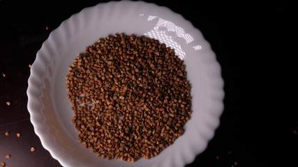 Buckwheat falls on a white plate, a black background.