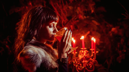 Naklejka premium Beautiful witch with the glass of vine on the night forest background.