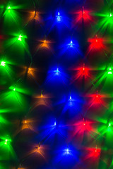 Obraz premium Background image of varicolored lights of a garland in a row on the wall closeup 