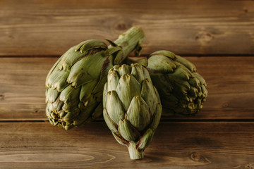 Obraz premium Natural artichokes on a rustic wooden table.