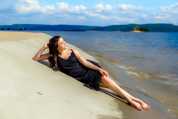 young beautiful girl lies on the river bank
