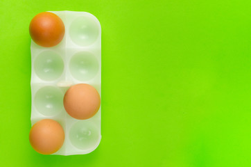 Three eggs in stand for egg a bright green background.