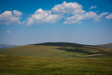 Blue sky puffy clouds and green hills