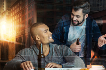 Emotional talk. Cheerful smiling young friends looking happy while drinking tasty beer and having an interesting talk together