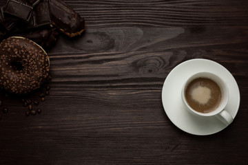 cup with coffee and chocolate donut on a dark background