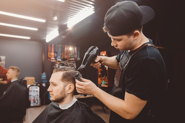 Barber shop. Man with wife in barber's chair, hairdresser Barbershop styling his hair