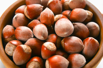 Hazelnut nuts in a wooden bowl on a white wooden table. Superfood.