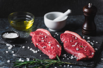 Two raw picanha steaks on a cutting board with spices on a dark background