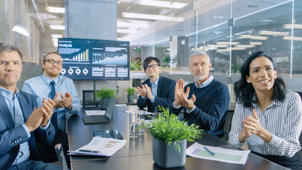 In the Conference Room Board of Directors Applaud Spokesperson. POV View Footage. In the Background TV Showing Statistics.