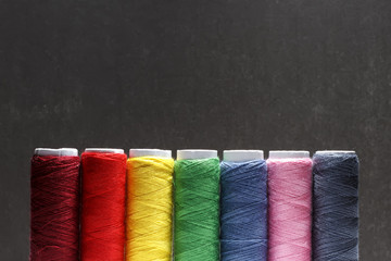 Set of pastel colors thread for sewing on a black background. Set of threads on bobbins retro style. Vintage accessories for sewing on the table. Multicolor spools of thread isolated