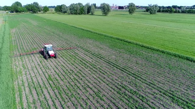Aerial corn field and tractor spraying agrochemical or agrichemical over the young maize field in most cases agrichemical refers to pesticides like insecticides herbicides fungicides and nematicides