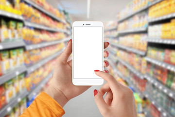 Female hand holding mobile smart phone with isolated white screen in supermarket