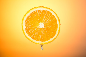 half an orange with a drop of water on a colored background, concept healthy eating