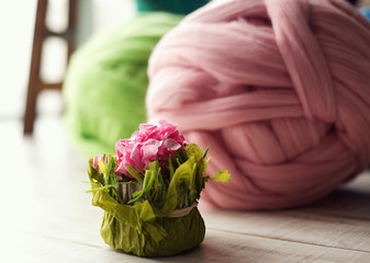 Colored skeins of wool in the foreground flowers