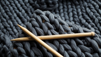 wooden knitting needles on background of grey merino