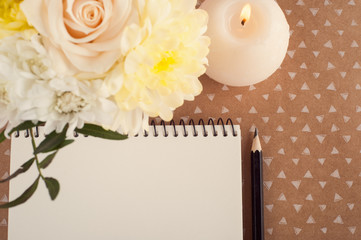 Obraz na płótnie Canvas Notebook, flowers and lit candle