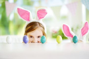 Two cute little sisters wearing bunny ears playing egg hunt on Easter