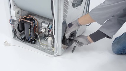 A repairman is fixing a drain pump filter on a washing machine. He needs to find out where the problem is.