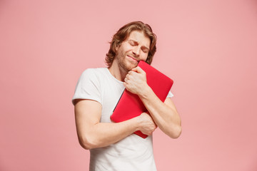 Businessman hugging laptop on pink