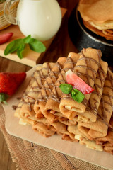 Pile of rolled crepes with banana filling on a wooden board
