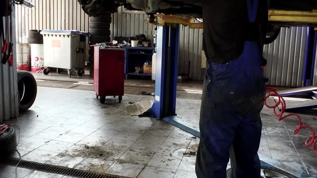 Auto mechanic working at auto repair shop. tilt up.
