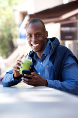 charming African american man sitting with cellphone and drink
