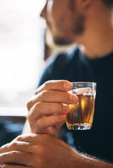 glass with a cold refreshing brown tea in the hand of a man in the background of a cafe. vertical photo.