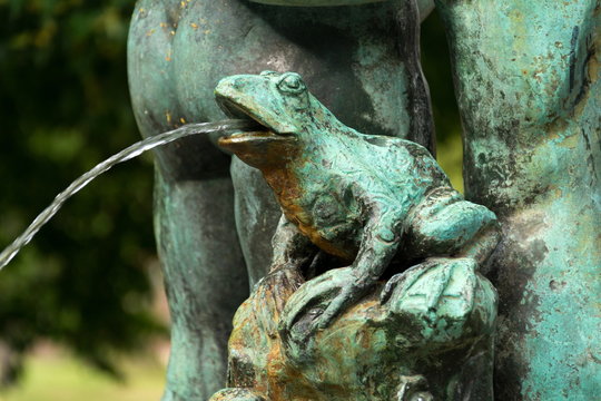 Frog splashing water on fountain in Petrin park, Prague, Czech Republic, water shortage scarcity concept