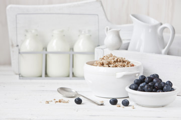 Granola, blueberries and milk healthy breakfast. Close-up, selective focus, shallow depth of field. White vintage background