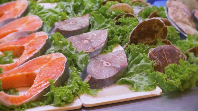 Showcase with sliced red fish on ice. Market. Fish in the shop window. Raw seafood is sold in the store. Closeup. 4k