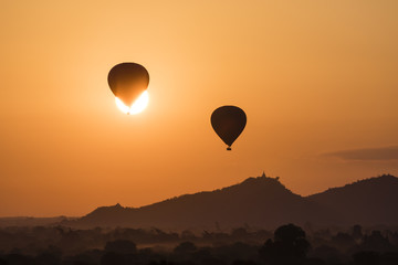 Balloon silhouettes in front of the sun over the ancient temples in Bagan during sunrise, Myanmar