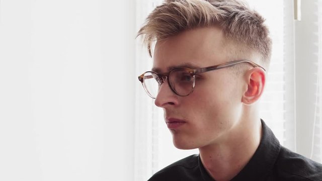 Handsome young man in glasses looking away and turns head