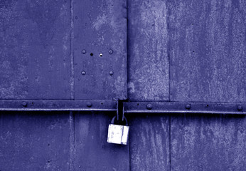 Old padlock on metal gate in blue tone.