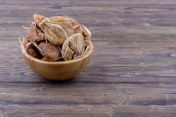 Dried figs in a wooden cup on a wooden background. Side view.