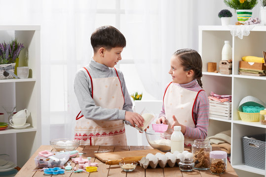 Girl and boy cooking in home kitchen, make the dough for baking, healthy food concept